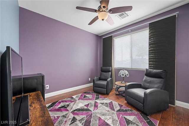 sitting room with a ceiling fan, wood finished floors, visible vents, and baseboards