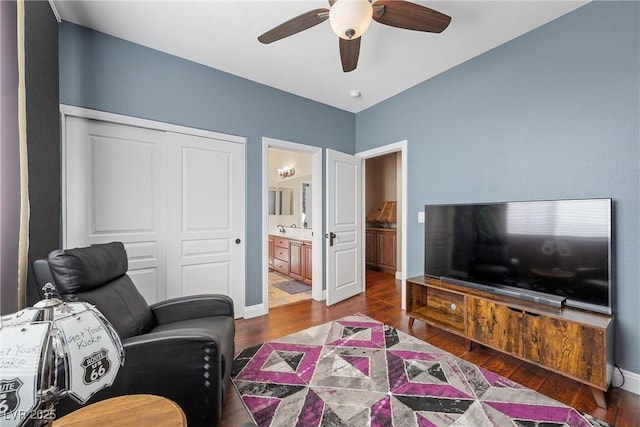 living area with dark wood-style floors, ceiling fan, and baseboards