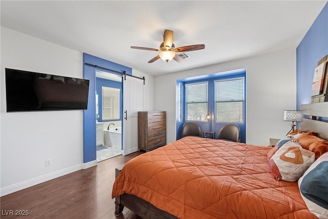 bedroom featuring a barn door, wood finished floors, a ceiling fan, baseboards, and ensuite bath