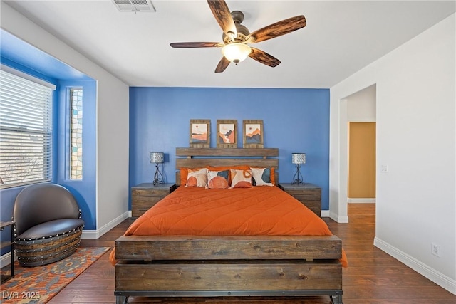 bedroom with a ceiling fan, wood finished floors, visible vents, and baseboards