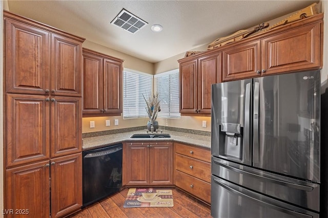 kitchen with stainless steel fridge, visible vents, dishwasher, brown cabinets, and a sink