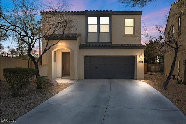 mediterranean / spanish-style house featuring concrete driveway, an attached garage, fence, and stucco siding