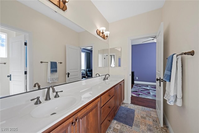 bathroom with double vanity, a sink, and baseboards