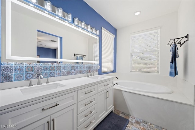 bathroom with double vanity, a sink, and a bath