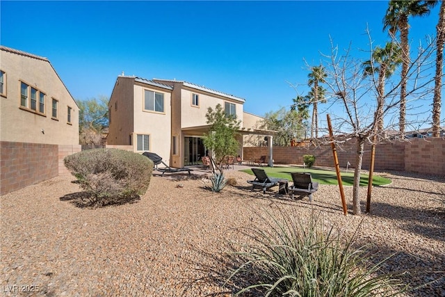 rear view of property featuring a patio area, a fenced backyard, and stucco siding