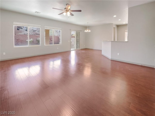 empty room featuring recessed lighting, ceiling fan with notable chandelier, wood finished floors, visible vents, and baseboards