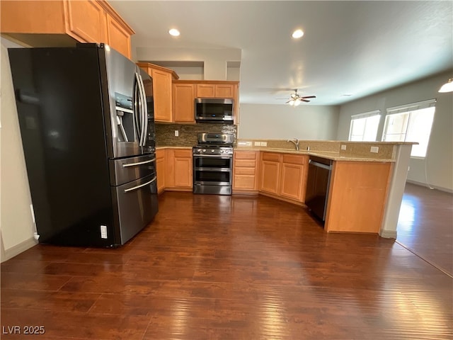 kitchen featuring light countertops, decorative backsplash, appliances with stainless steel finishes, dark wood-type flooring, and a peninsula