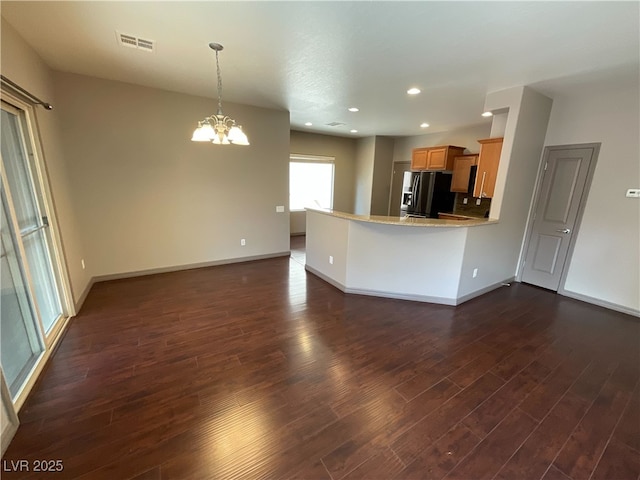 kitchen featuring dark wood-style floors, visible vents, fridge with ice dispenser, and a peninsula