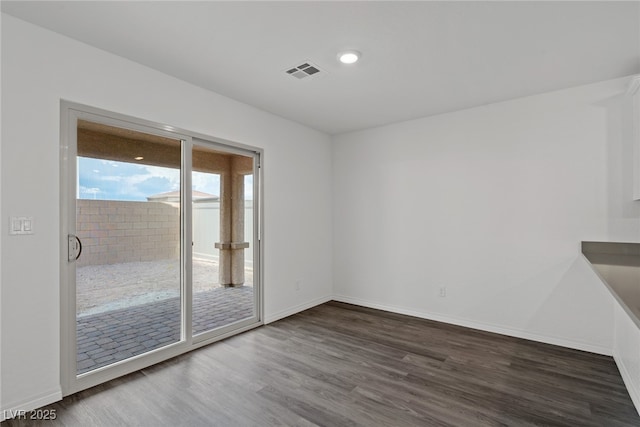 empty room with baseboards, visible vents, and wood finished floors