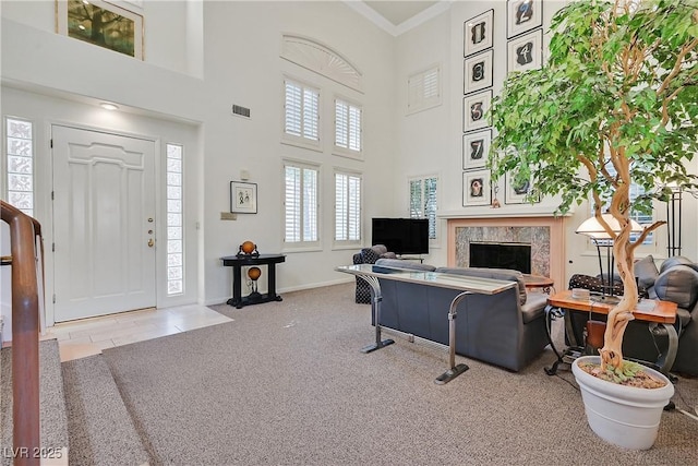 living room with ornamental molding, a high end fireplace, a high ceiling, carpet flooring, and baseboards