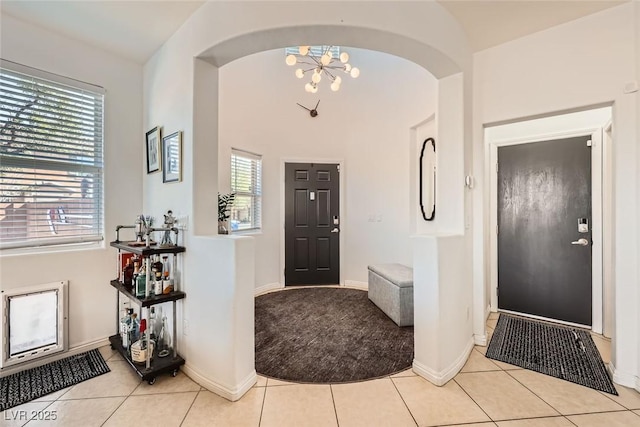 tiled entrance foyer featuring baseboards and a chandelier