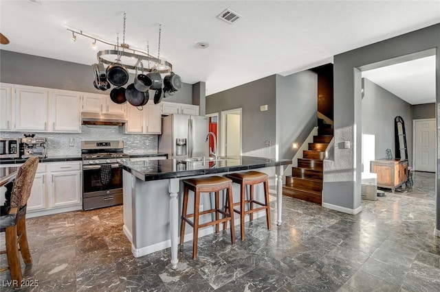 kitchen with under cabinet range hood, visible vents, appliances with stainless steel finishes, and marble finish floor