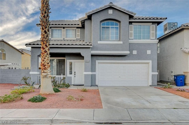 view of front of home with an attached garage, fence, driveway, a tiled roof, and stucco siding