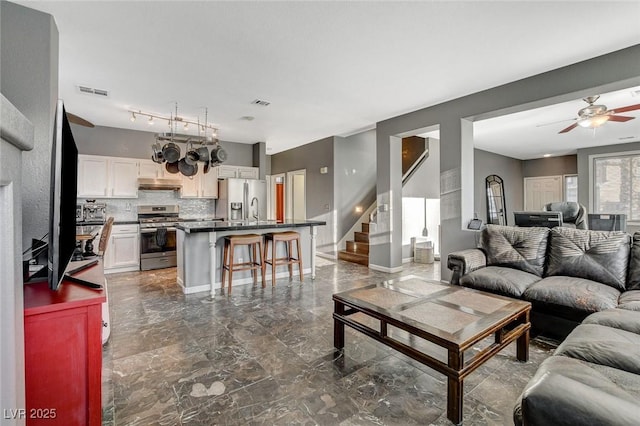 living room featuring marble finish floor, visible vents, ceiling fan, and stairs