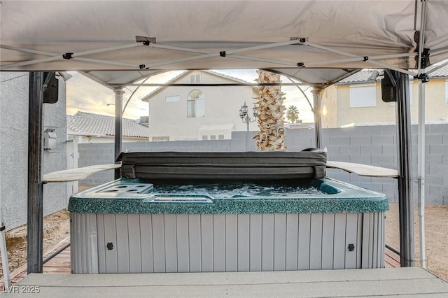 view of patio / terrace with a hot tub and fence