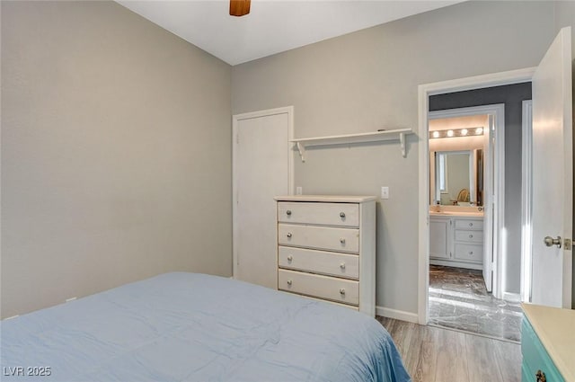 bedroom featuring baseboards, ceiling fan, ensuite bath, and wood finished floors