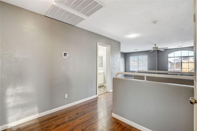 hallway with dark wood-type flooring, visible vents, and baseboards