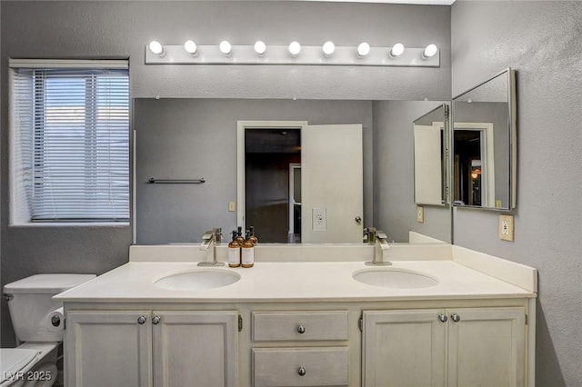 full bath featuring a textured wall, double vanity, and a sink