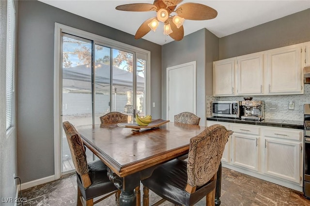 dining space featuring a ceiling fan and baseboards