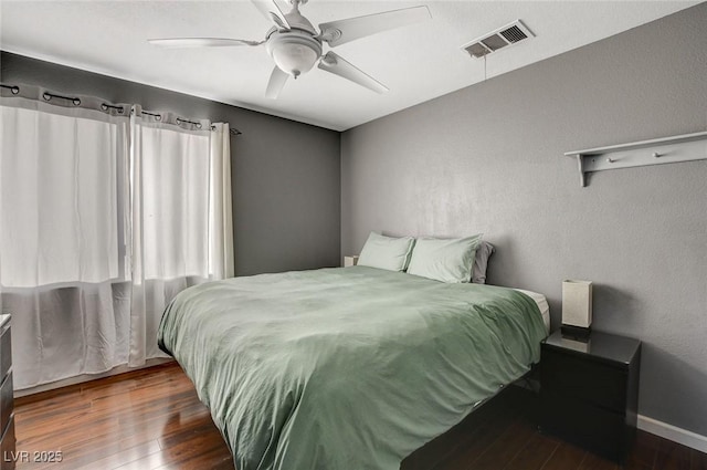 bedroom featuring a ceiling fan, wood finished floors, visible vents, and baseboards