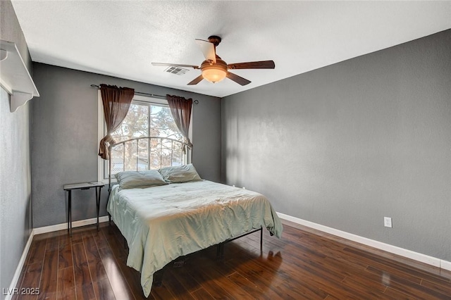 bedroom with ceiling fan, visible vents, baseboards, and wood finished floors