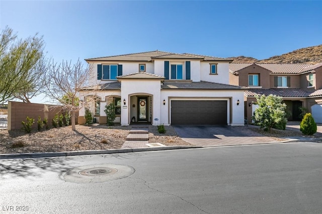 view of front of home featuring a garage, decorative driveway, fence, and stucco siding