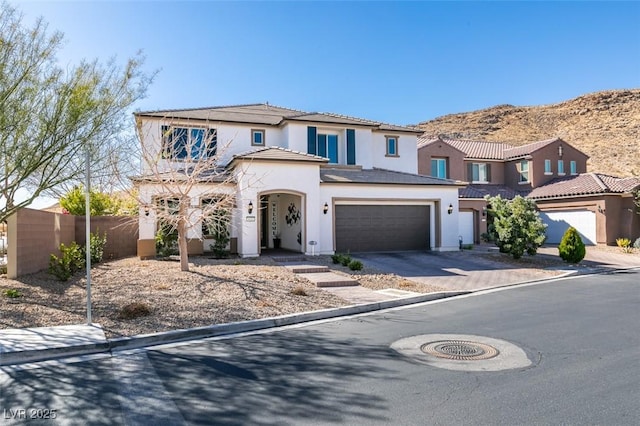 mediterranean / spanish home featuring stucco siding, concrete driveway, an attached garage, a mountain view, and fence