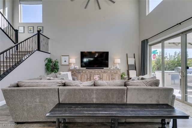 living area featuring a high ceiling, stairway, wood finished floors, and baseboards