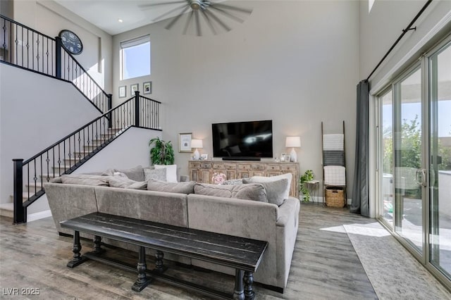 living area with plenty of natural light, stairway, baseboards, and wood finished floors