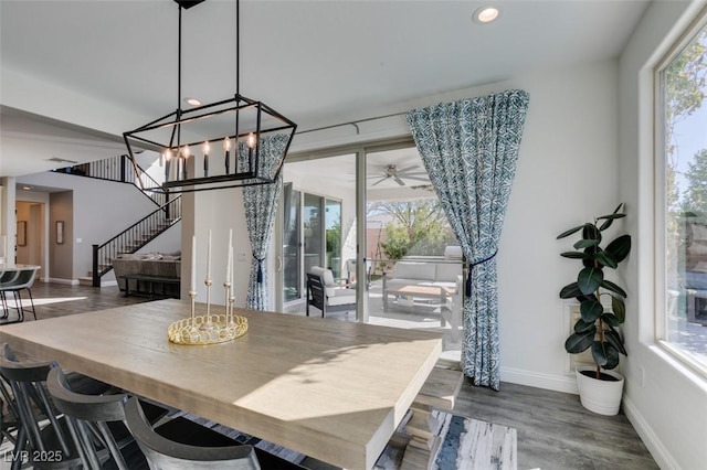 dining room with a wealth of natural light, wood finished floors, baseboards, and stairs