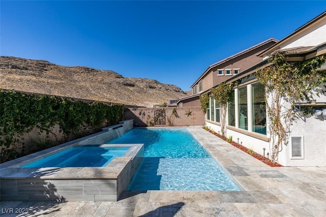 view of swimming pool with an in ground hot tub, a patio, a fenced backyard, and a mountain view