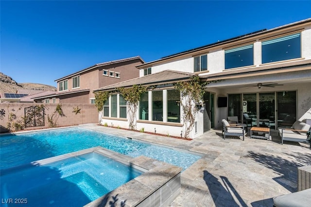 back of property featuring stucco siding, a pool with connected hot tub, a patio area, ceiling fan, and fence