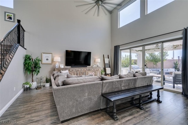 living room with a high ceiling, stairway, baseboards, and wood finished floors