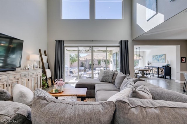 living area featuring a high ceiling, baseboards, and wood finished floors