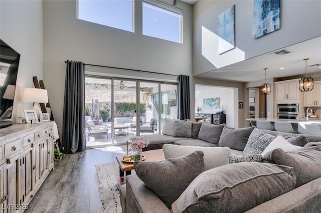 living area with a chandelier, french doors, visible vents, and wood finished floors