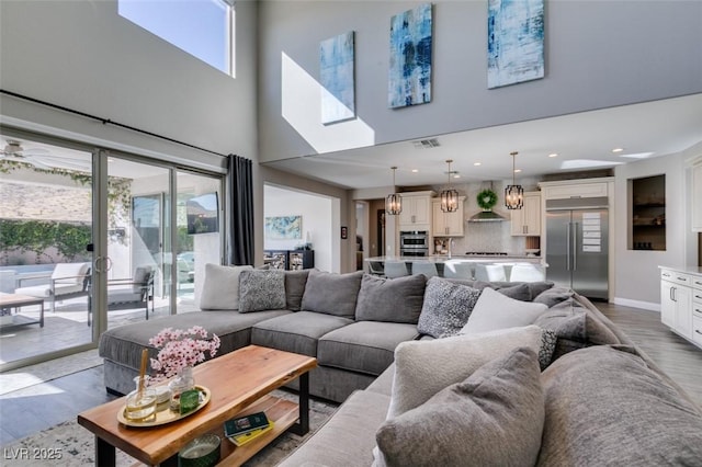 living area with a healthy amount of sunlight, visible vents, baseboards, and wood finished floors