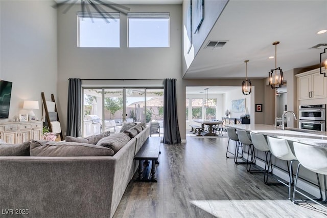 living area featuring a high ceiling, visible vents, dark wood finished floors, and recessed lighting