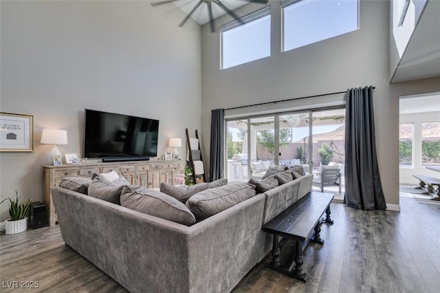 living room with a high ceiling, dark wood-style flooring, and baseboards