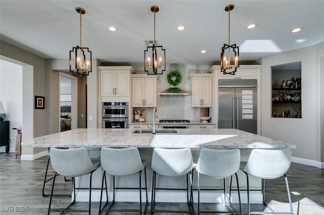 kitchen with a large island, stainless steel appliances, tasteful backsplash, a sink, and baseboards