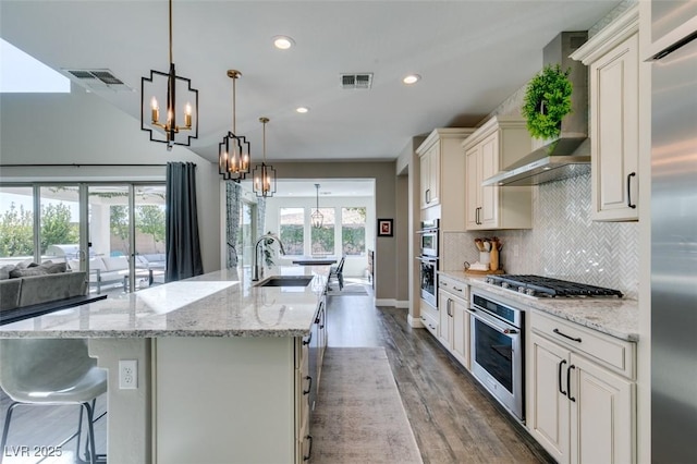 kitchen with stainless steel appliances, visible vents, a sink, and wall chimney exhaust hood