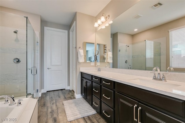 full bathroom with a shower stall, visible vents, a sink, and wood finished floors