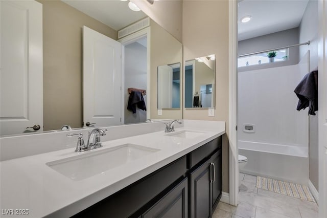 bathroom featuring double vanity, shower / bath combination, a sink, and toilet