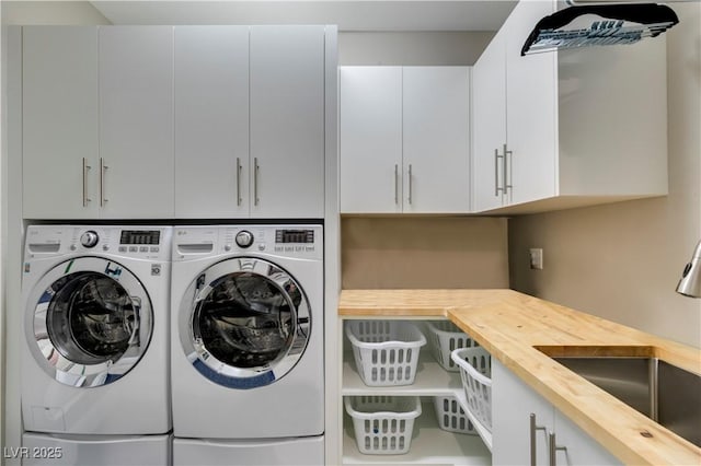 washroom with cabinet space, washing machine and dryer, and a sink