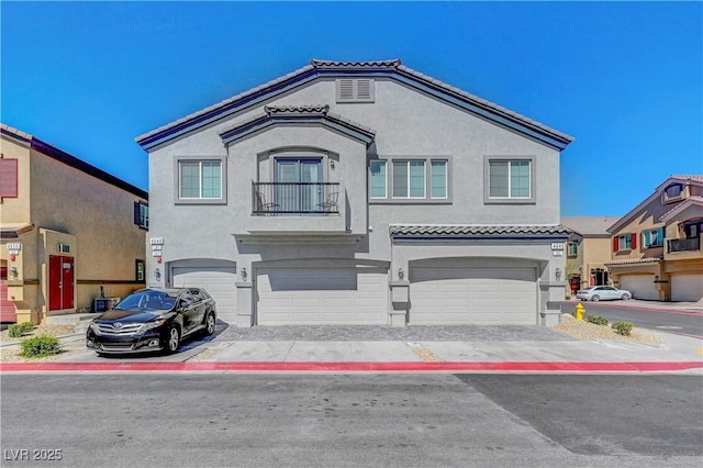 view of front of property featuring a tiled roof, a balcony, an attached garage, and stucco siding