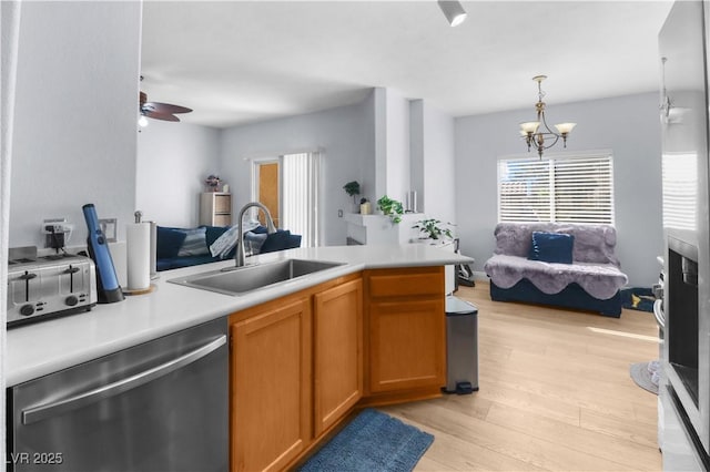 kitchen with open floor plan, light countertops, stainless steel dishwasher, and a sink