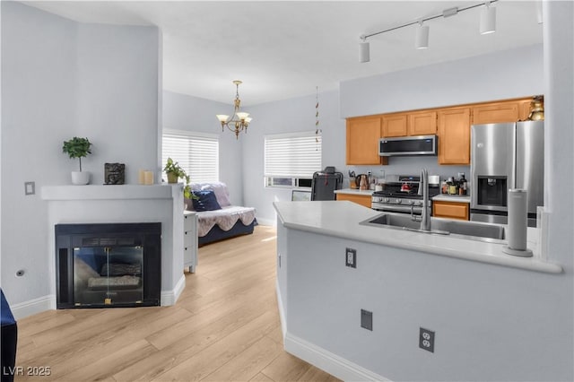 kitchen featuring light countertops, appliances with stainless steel finishes, a sink, light wood-type flooring, and a peninsula