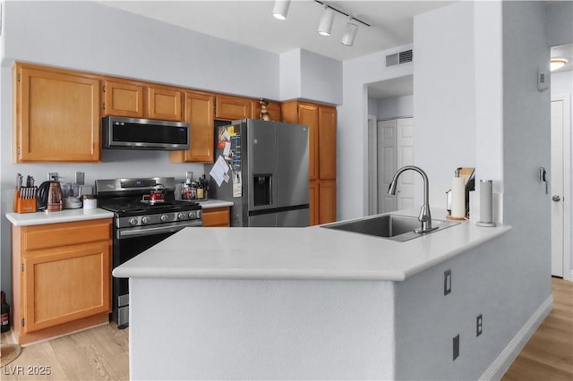 kitchen with appliances with stainless steel finishes, light wood-type flooring, visible vents, and a sink