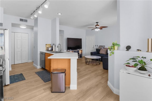 kitchen featuring light wood-style flooring, a peninsula, a sink, visible vents, and dishwasher