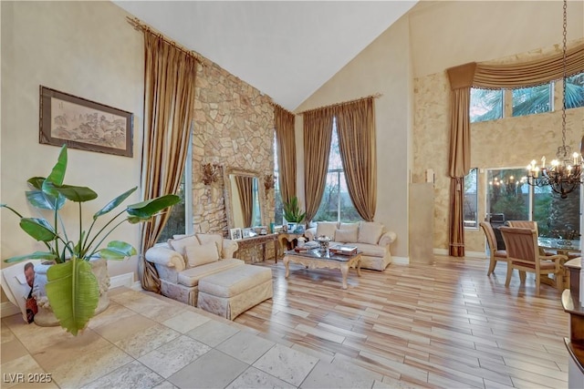 sitting room with high vaulted ceiling, a notable chandelier, light wood finished floors, and baseboards