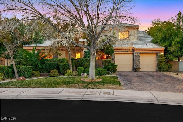 view of front of home featuring a garage, stone siding, decorative driveway, and stucco siding